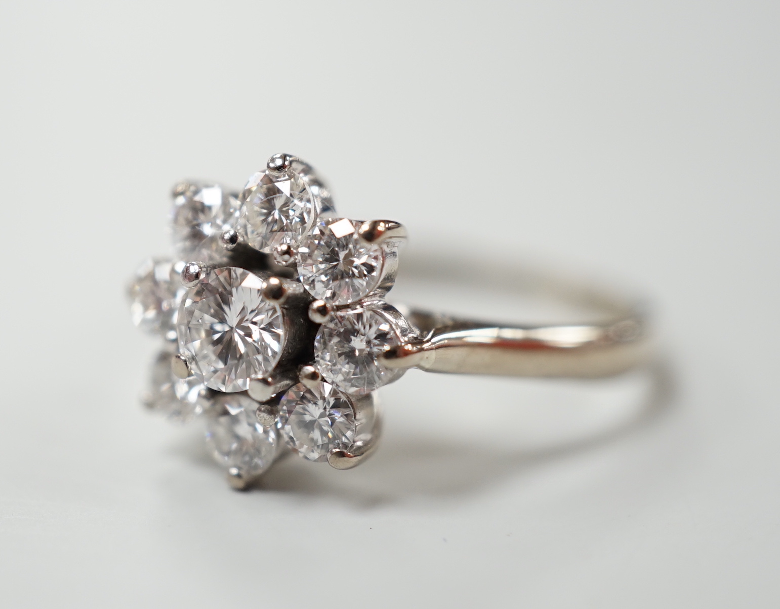 An 18ct, plat. and nine stone diamond set flower head cluster ring, the central stone weighing approximately 0.25ct, size O, gross weight 4 grams.
